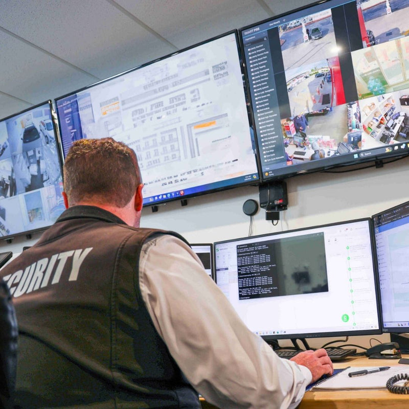 Security officer monitoring multiple screens in a control room.