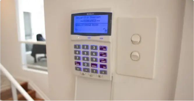 Digital security keypad on a wall with a blurred indoor background