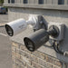 Two Hikvision bullet security cameras shown on a white background, one in white and one in black, both with visible wall-mount flanges.